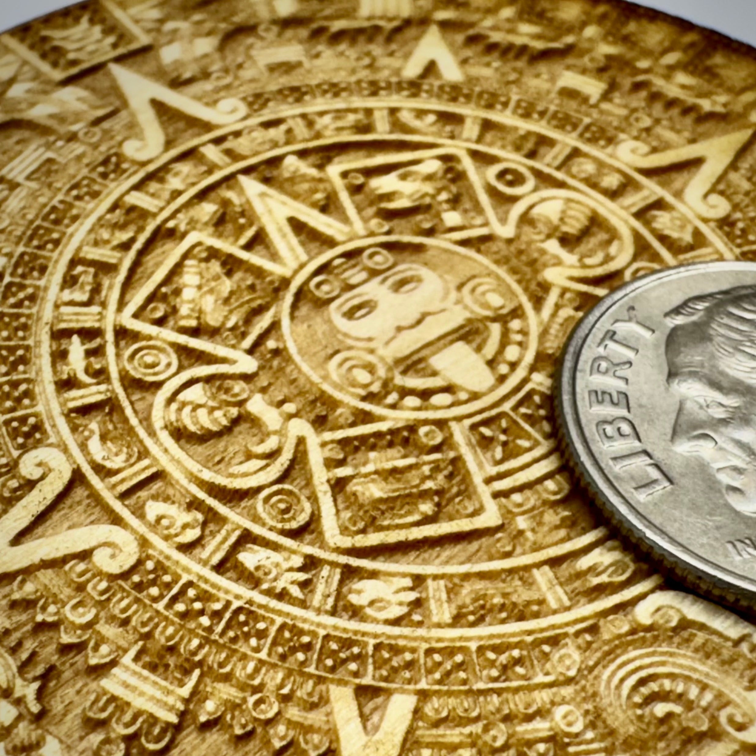 Engraved Aztec calendar with a silver coin on top